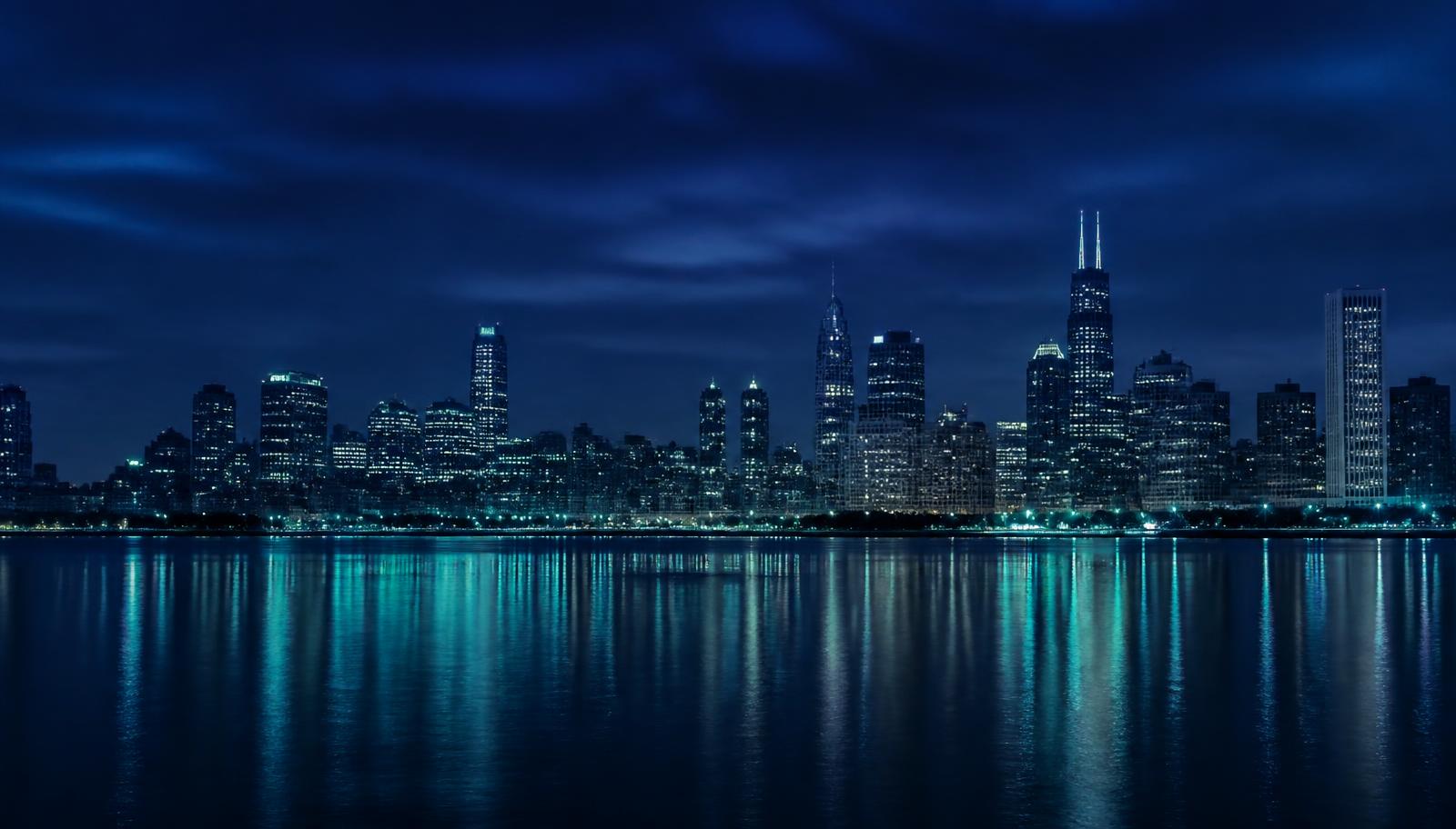 A city skyline at blue hour reflected across calm water